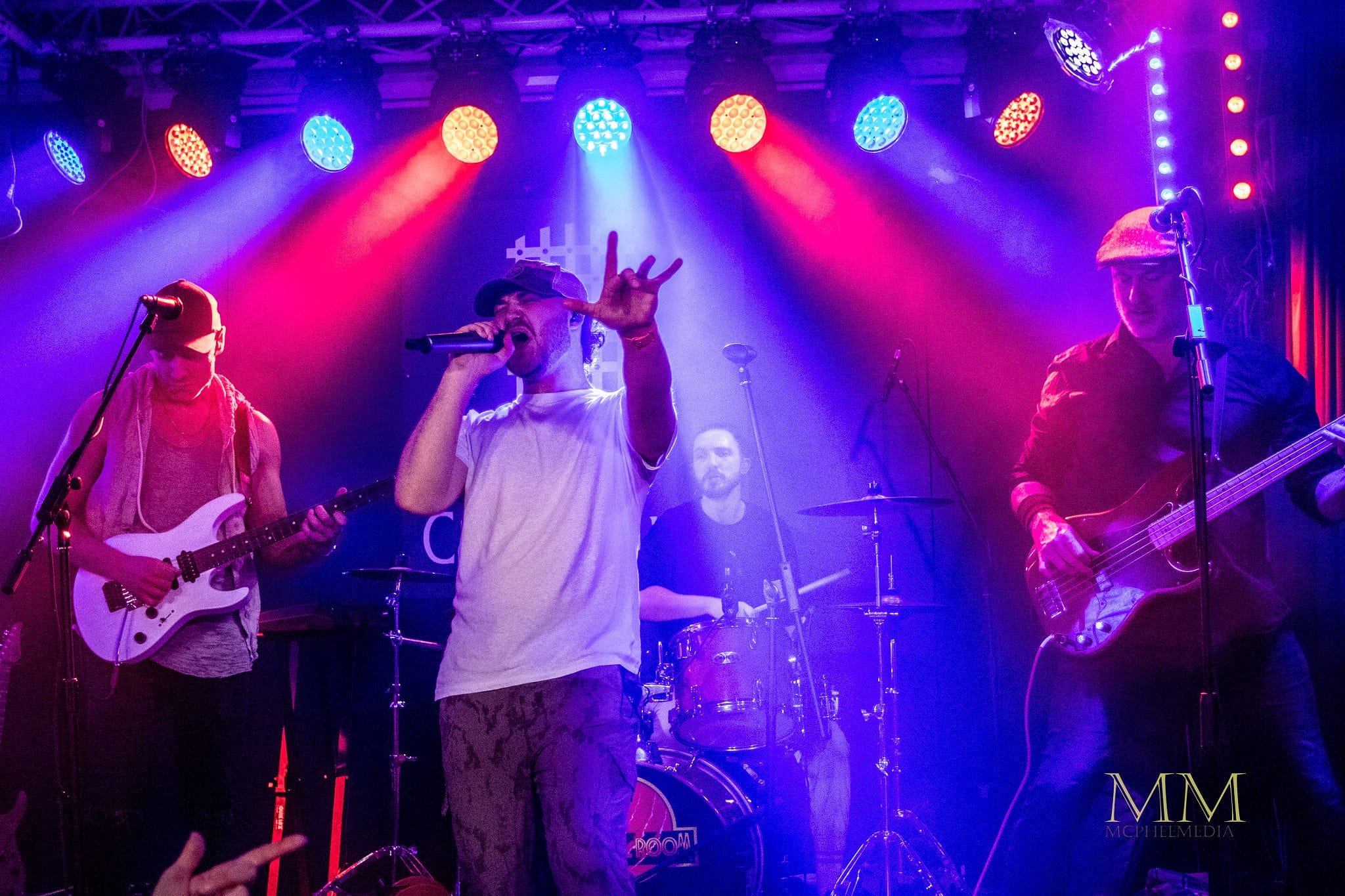 Animal Room’s vocalist, guitarists, bassist and drummer playing under red and blue stage lights.